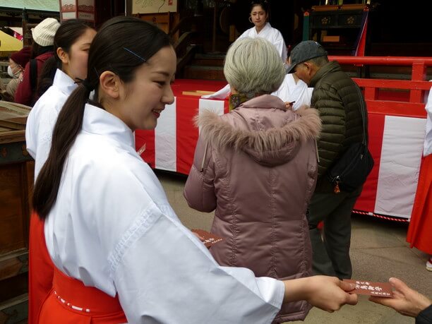 鷽鳥のお守りを渡す巫女さん