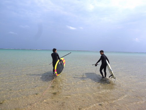 ボードをもって海へ向かう二人