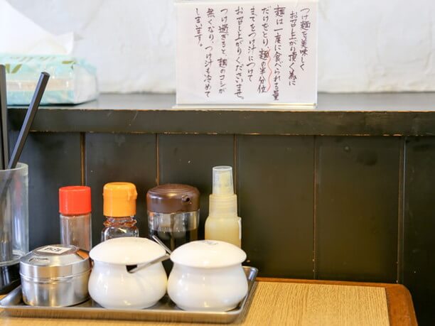 テーブルの上にセットされた調味料とつけ麺の美味しい食べ方